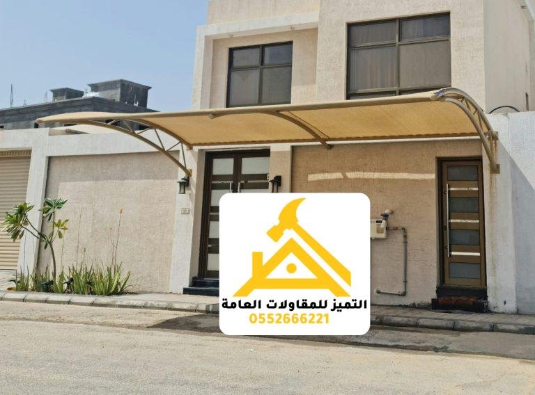 مظلة سيارة قماشية بهيكل معدني داكن أمام مدخل فيلا