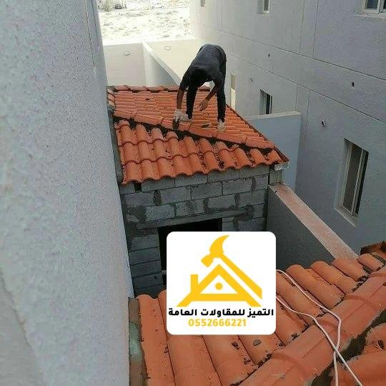 عامل يرص القرميد على سقف مبنى صغير