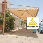 عمال أثناء تركيب مظلة سيارة قماشية فوق ممر السيارات