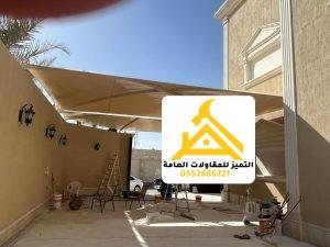 مظلة قماشية بيج مثبتة على جدار المنزل تغطي الفناء