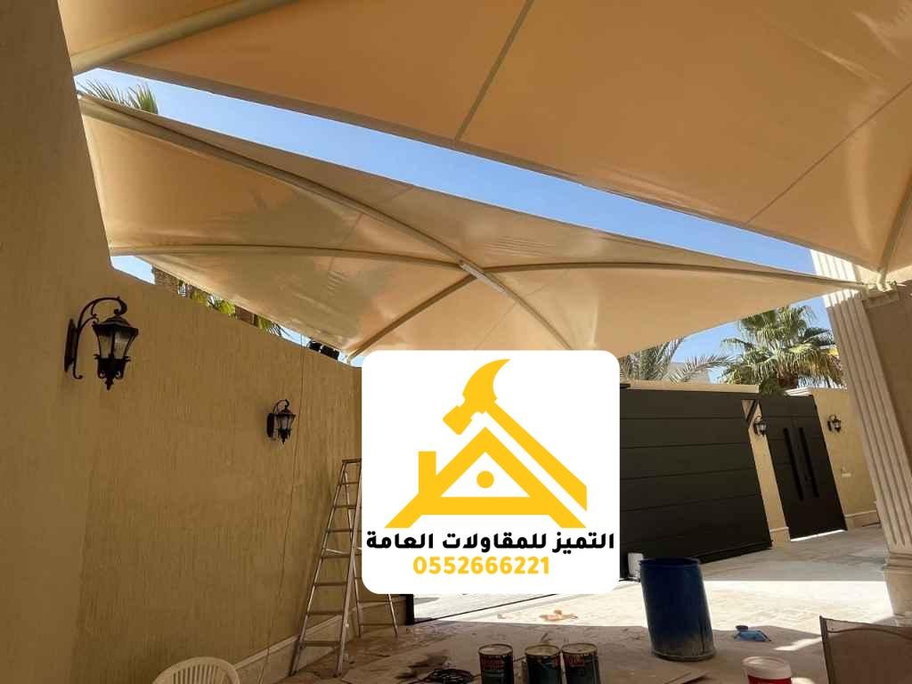 مظلة قماشية بيج مثبتة على جدار داخل فناء