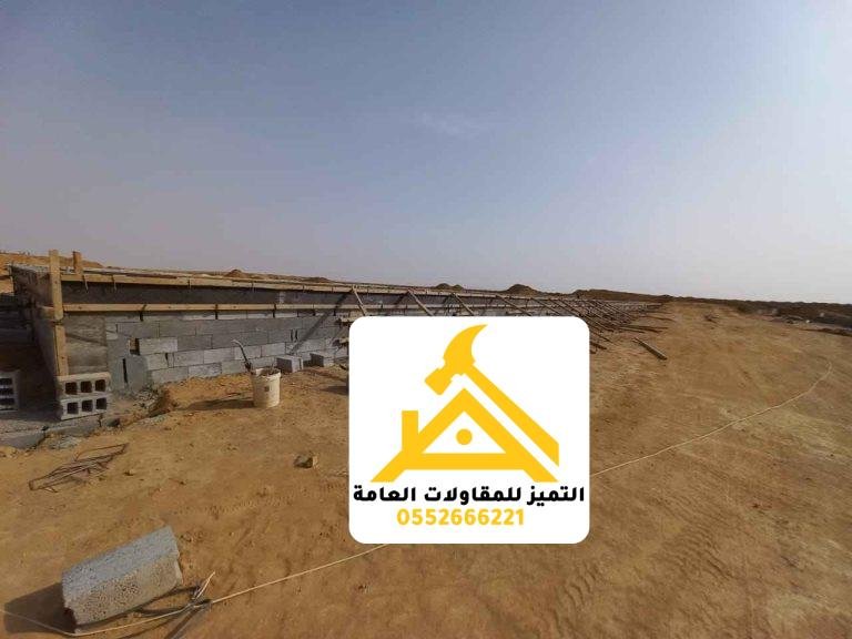 قاعدة وجدار منخفض يمتدان على طول منشأة معدنية قيد الإنشاء