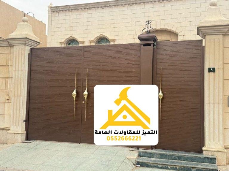 بوابة سيارات حديد بضلفتين بلون بني ومقابض ذهبية بين أعمدة حجرية