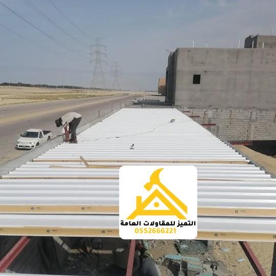 عمال يركّبون ألواح سقف ساندوتش بانل على الهيكل