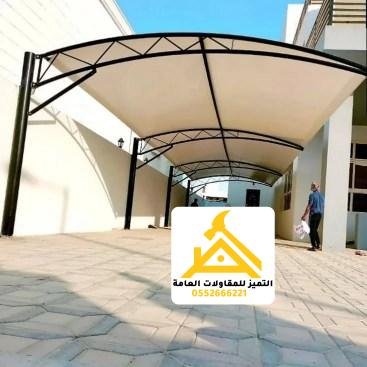 مظلة كابولية بهيكل مقوّس أسود فوق ممر مدخل