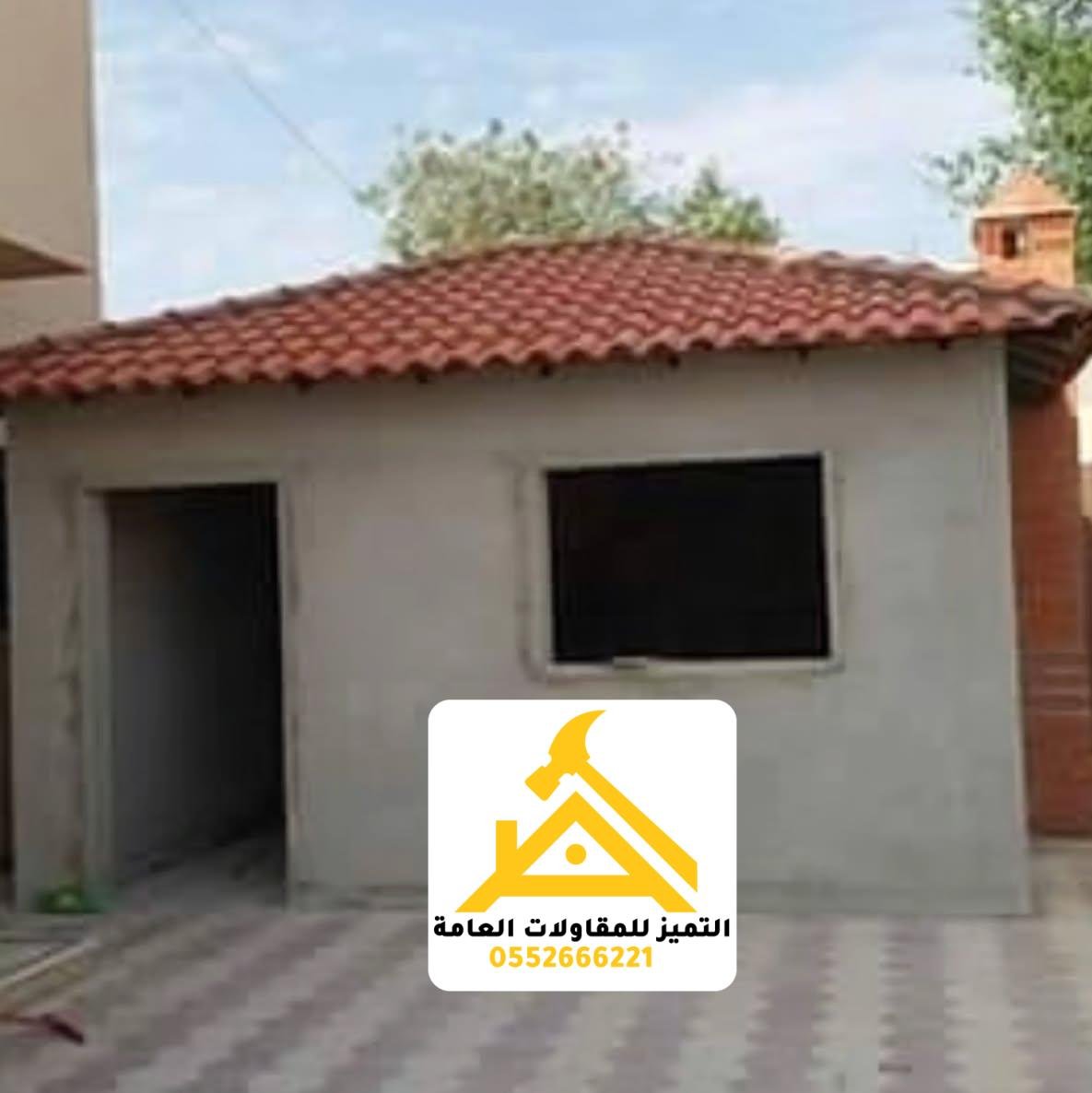 ملحق صغير بجدران مشطّبة وسقف قرميد أحمر بأربعة ميول في فناء مبلّط