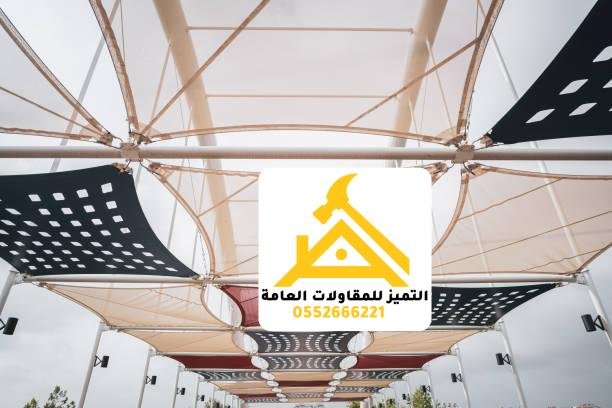 أشرعة قماش بيضاء وأخرى مثقبة تغطي مساحة مفتوحة بارتفاعات متدرجة