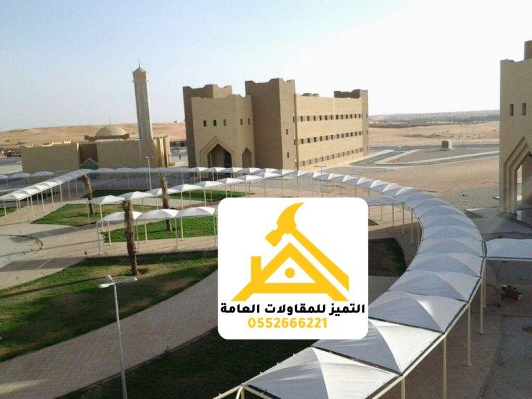 صف منحنٍ من مظلات الشد البيضاء بجوار مبنى مؤسسي