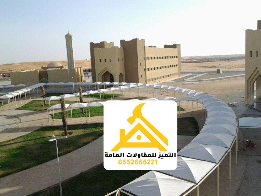 مظلات مواقف سيارات بيضاء تمتد على مسار منحنٍ بجوار مبنى حكومي