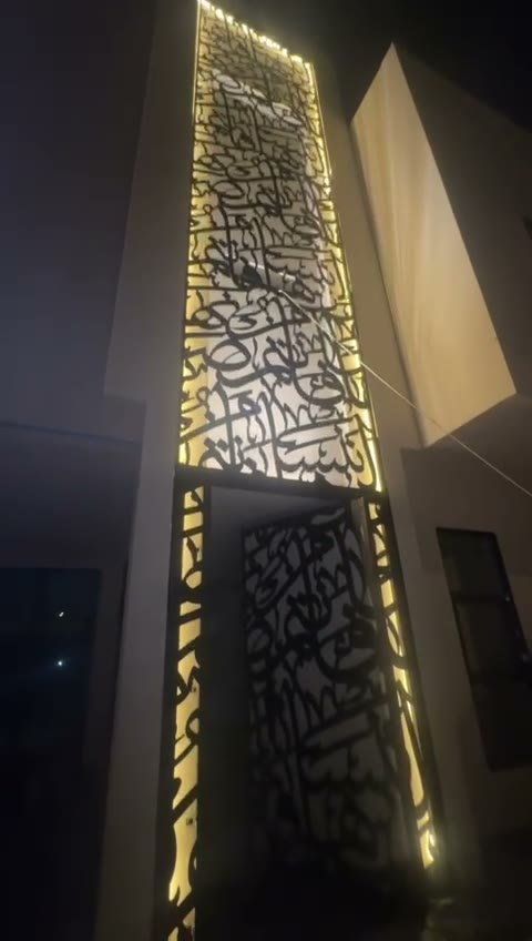 مدخل فيلا ليلًا بباب حديد قص ليزر ولوح خط عربي علوي مضاء